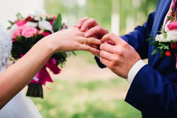 Brudgummen sätter en vigselring på fingret brudar — Stockfoto