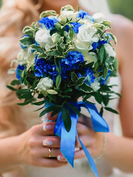 Svatební kytice s bílými růžemi a modrými květy v rukou nevěsty s kroužkem — Stock fotografie