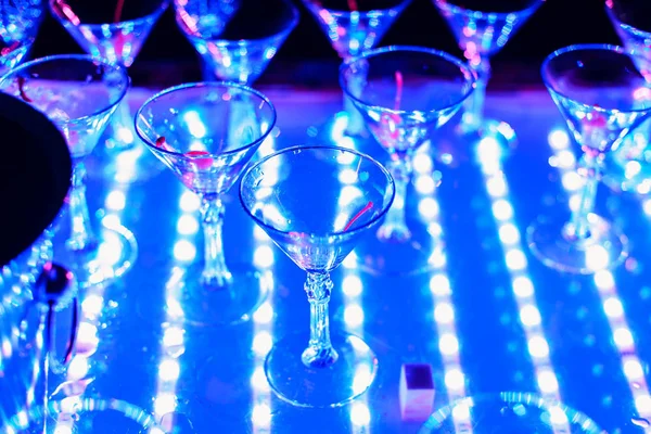 Copos vazios de coquetéis na festa de férias com uma luz de fundo azul — Fotografia de Stock