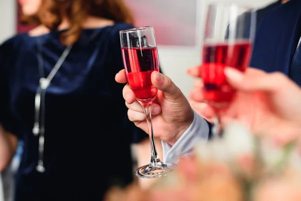 Sklo červené šampaňského v ruce muže v obleku na festivalu — Stock fotografie
