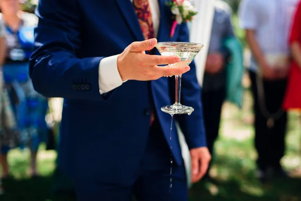 Hand with a glass of Martini in the hand of the groom at the wedding — Stock Photo, Image