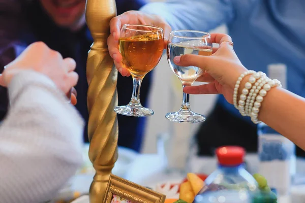 节日餐桌上的人们手中的白葡萄酒杯 — 图库照片