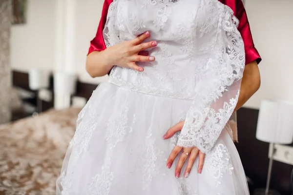 Novia sostiene un vestido blanco de boda — Foto de Stock