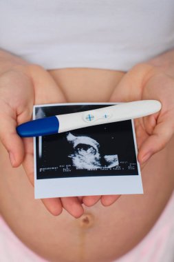 Ultrason resmini ve hamile bir kız elinde pozitif gebelik testi