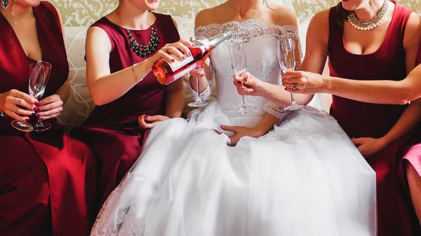 bride and her friends in red dresses at wedding pour champagne on glasses
