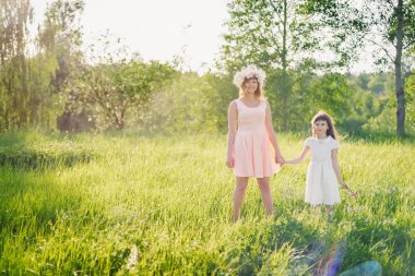 Anne ve kızı sahada günbatımı güneşli yaz gününde yürüyüş