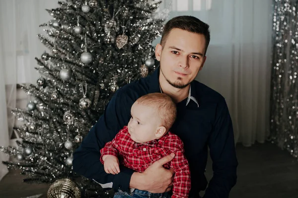 Bambino bambino tra le braccia del padre sullo sfondo dell'albero di Natale — Foto Stock
