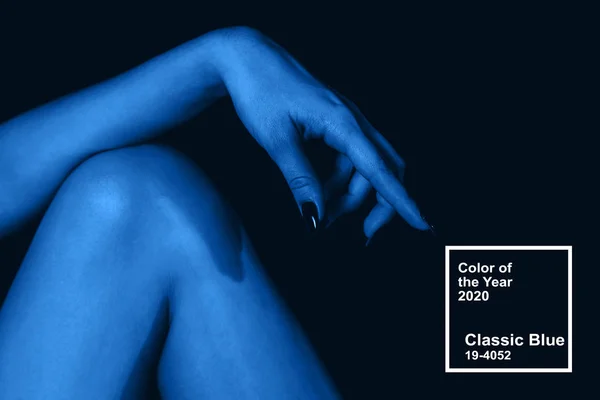 Klassieke blauwe kleur van het jaar 2020. vrouwelijke hand op knie — Stockfoto