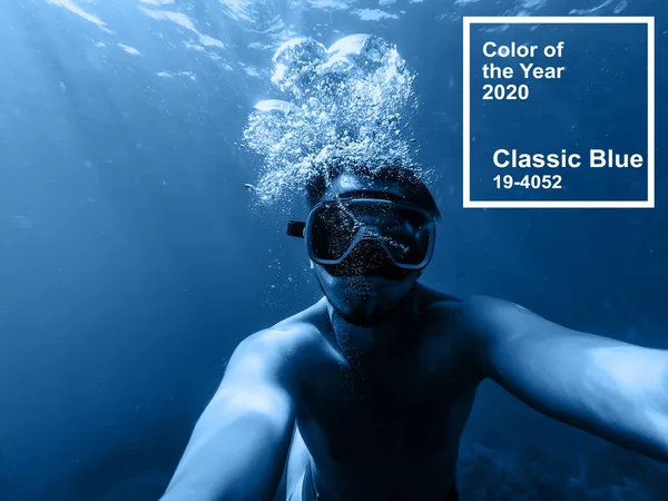 Classic Blue pantone color of the Year 2020. male diver swims in the sea under water with a mask and snorkel