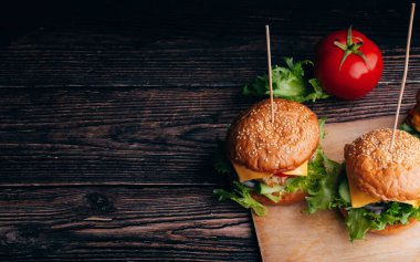 Etli, peynirli, marullu, domatesli ve soğanlı iki lezzetli hamburger.