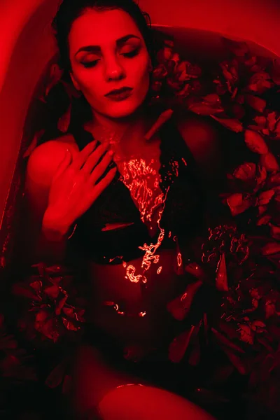 Молода сексуальна дівчина насолоджується ванною з пелюстками квітів — стокове фото