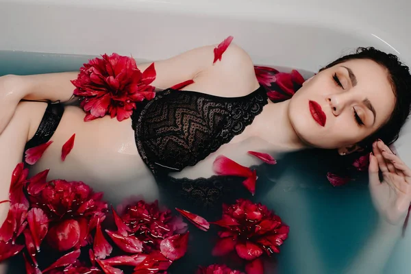 Girl in lingerie enjoys in bath with flower petals — ストック写真