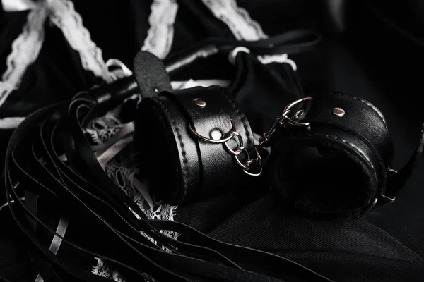 Leather handcuffs and whip for BDSM and maid costume for role-playing games — Stock Photo, Image