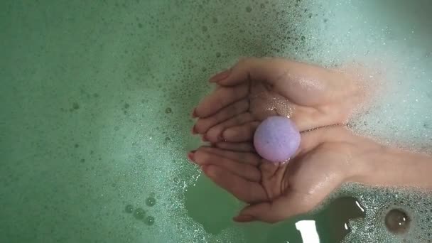 Bomba fürdő só feloldódik a vízben, és létrehoz hab a nők kezében — Stock videók