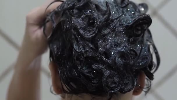 Mladá brunetka dívka myje a stará se o vlasy na hlavě — Stock video