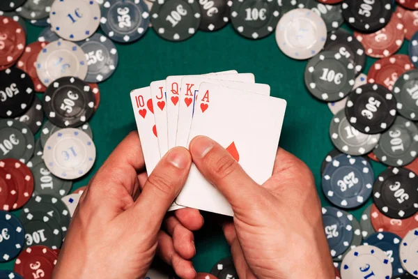 Royal flush in het spel van poker in de handen van de speler op de achtergrond van een groene tafel met gaming chips — Stockfoto