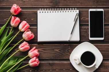 bir fincan kahve ve bir ahşap masa üstünde bir smartphone ile Pembe Lale buketi