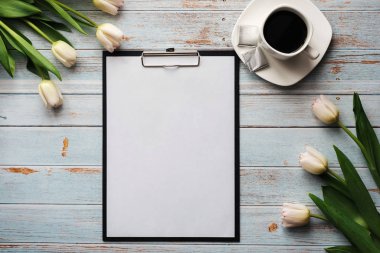 boş bir kağıt tablet ve ahşap bir masa üzerinde bir Fincan kahve ile beyaz lale buketi