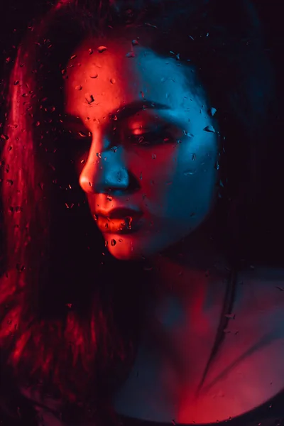 Portret smutnej dziewczyny z naciskiem na szkło z krople deszczu — Zdjęcie stockowe