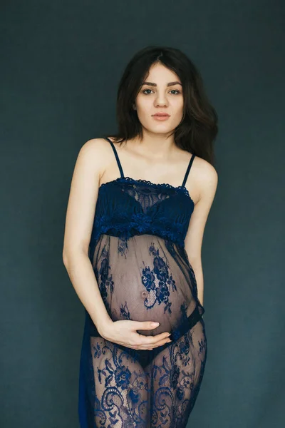 Embarazada atractiva morena joven mamá chica mantiene su vientre en un hermoso negligee —  Fotos de Stock