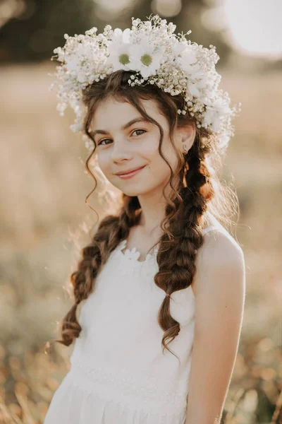 Muotokuva hymyilevä nuori tyttö valkoinen mekko ja kukka seppele hänen hiukset punokset kesäkentällä — kuvapankkivalokuva