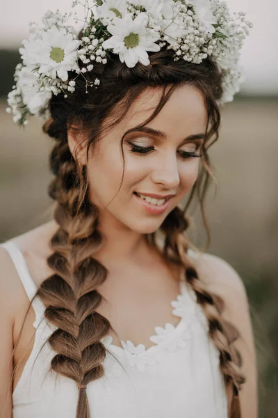 Szczęśliwy uśmiechający się dziewczyna z plecionki i wieniec kwiatowy w białej sukni w stylu boho w lato na zewnątrz — Zdjęcie stockowe