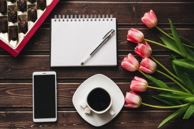 bir fincan kahve ve çikolata bir kutu ve akıllı telefon ile boş bir dizüstü bilgisayar ile pembe Lale çiçek buketi