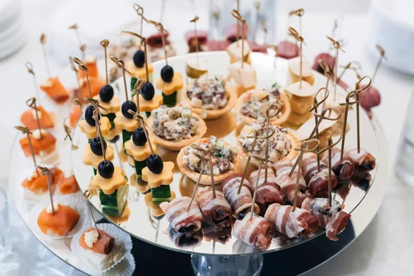 Canapés avec bacon, olives, fromage, concombre et poisson rouge sur une assiette — Photo