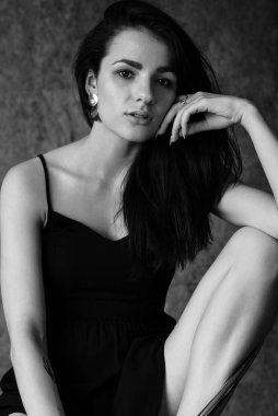 Siyah-beyaz bir esmer kız portresi. Uzun saçlı, elbiseli.