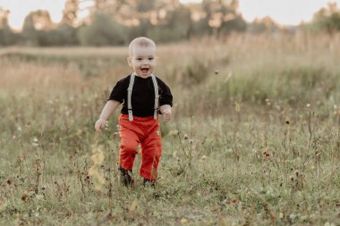 Bebek yaz tarlasında gülümsüyor ve çimenlerde koşuyor.