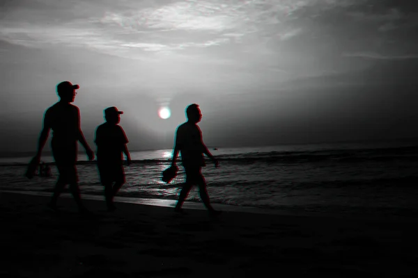 Силуэты мужчин на пляже у моря на фоне восхода солнца — стоковое фото