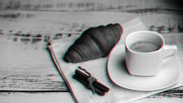 Tasse Kaffee und Croissant mit Zimtstangen auf Serviette auf einem Holztisch — Stockfoto