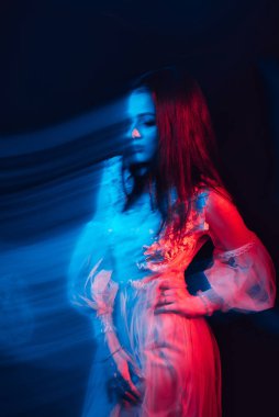 Esmer bir kızın soyut portresi koyu bir arka planda, bulanık bir etkiye sahip bir elbise içinde.