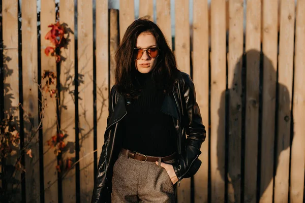 Portrait of a stylish young brunette girl in sunglasses and a leather jacket — Stock Photo, Image