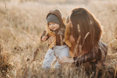 Genç anne sonbaharda küçük oğluyla oynuyor.