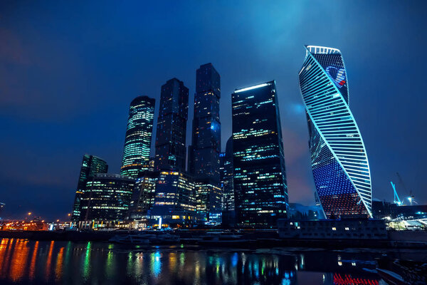 Высокие современные небоскребы Москвы с освещением и отражением в реке
