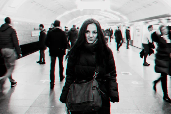 Young Caucasian girl at a metro station and a crowd of moving people with blur — Stock Photo, Image