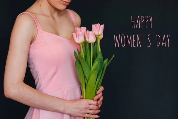 Boeket bloemen van roze tulpen in de handen van een meisje. Wenskaart met tekst Happy Womens Day — Stockfoto