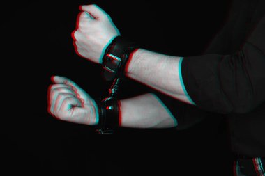 mans hands in leather handcuffs on black background