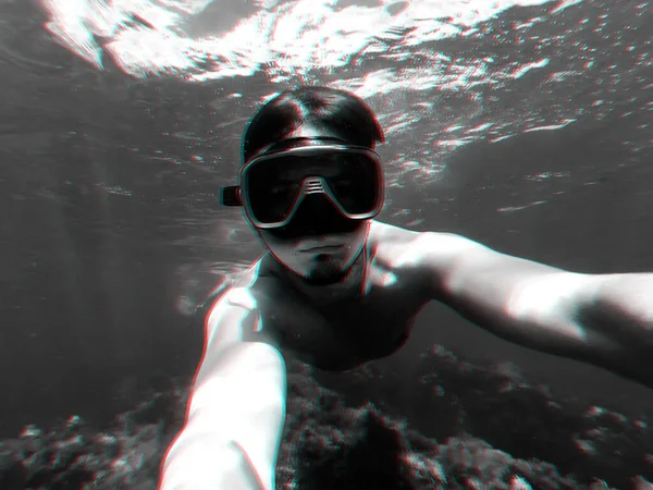 Unterwasserblick eines Tauchers, der mit Schnorchelmaske im türkisfarbenen Meer unter der Oberfläche schwimmt und ein Selfie macht — Stockfoto