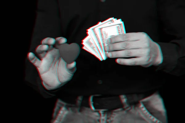 Billetes de dólar y un corazón rojo en manos de un hombre — Foto de Stock