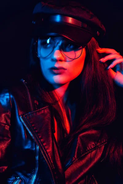 Stylish portrait of a young girl with glasses in a leather jacket and cap — Stock Photo, Image