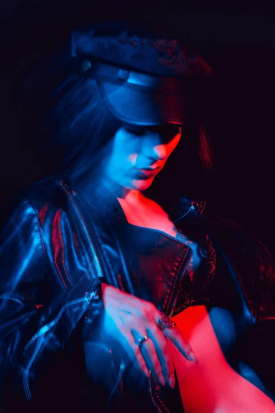 Stílusos portré egy fiatal lányról bőrdzsekiben és sapkában neon fénnyel — Stock Fotó