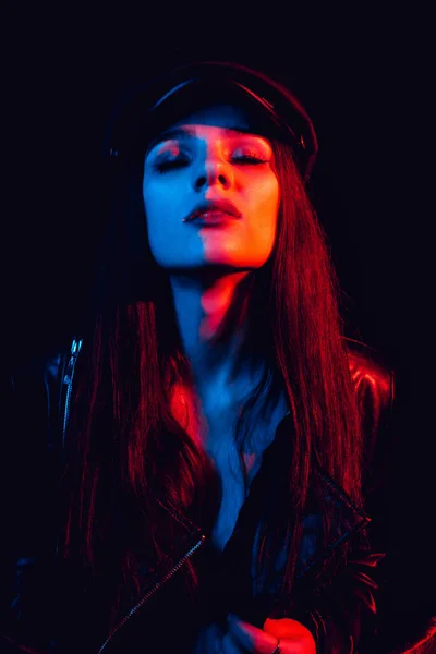 Модний портрет стильної дівчини в шкіряній куртці і кепці з неоновим світлом — стокове фото