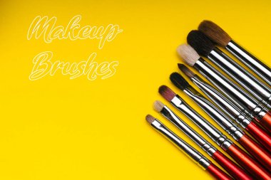 Sarı arkaplanda kırmızı makyaj fırçaları
