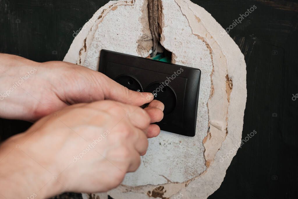 Замена и установка новой электрической розетки. Руки с отверткой ...