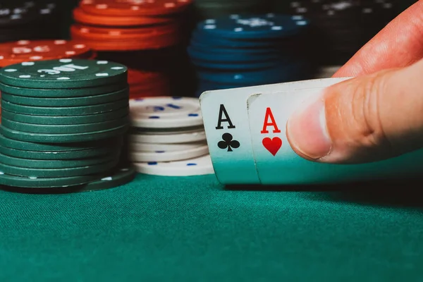 Jogador revela um par de ases no poker contra o fundo de jogar fichas na mesa verde — Fotografia de Stock