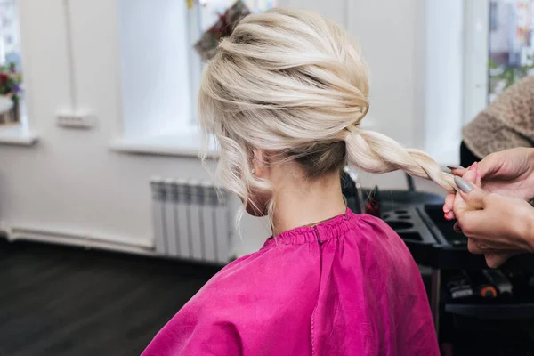 Mãos de um cabeleireiro fazer um penteado para uma menina loira — Fotografia de Stock