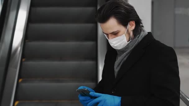 Erkek, COVID-19 Coronavirus salgınına karşı koruyucu bir maske ve eldiven takıyor. Cep telefonu kullanıyor. — Stok video