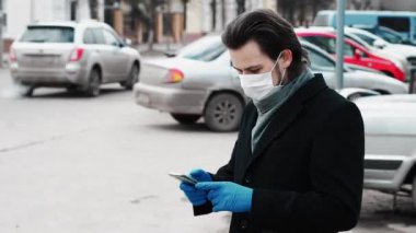 COVID-19 Coronavirus 'a karşı korumak için solunum maskesi ve eldiven takan beyaz Kafkas adam akıllı bir telefon kullanıyor.